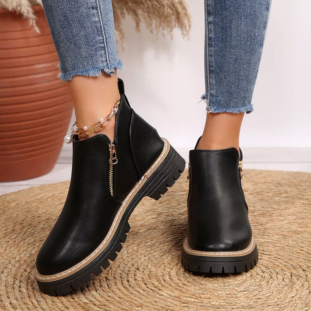 Black ankle boots with side zipper, tan stitching, and thick lug sole