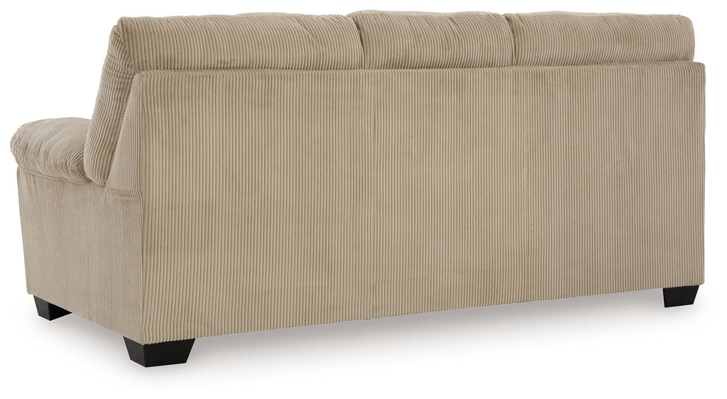 Upholstered sofa in beige fabric, side view with padded arm and boxy back