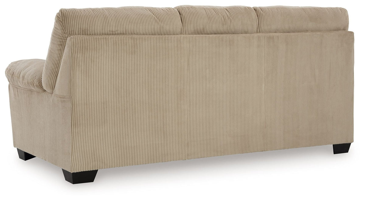 Upholstered sofa in beige fabric, side view with padded arm and boxy back