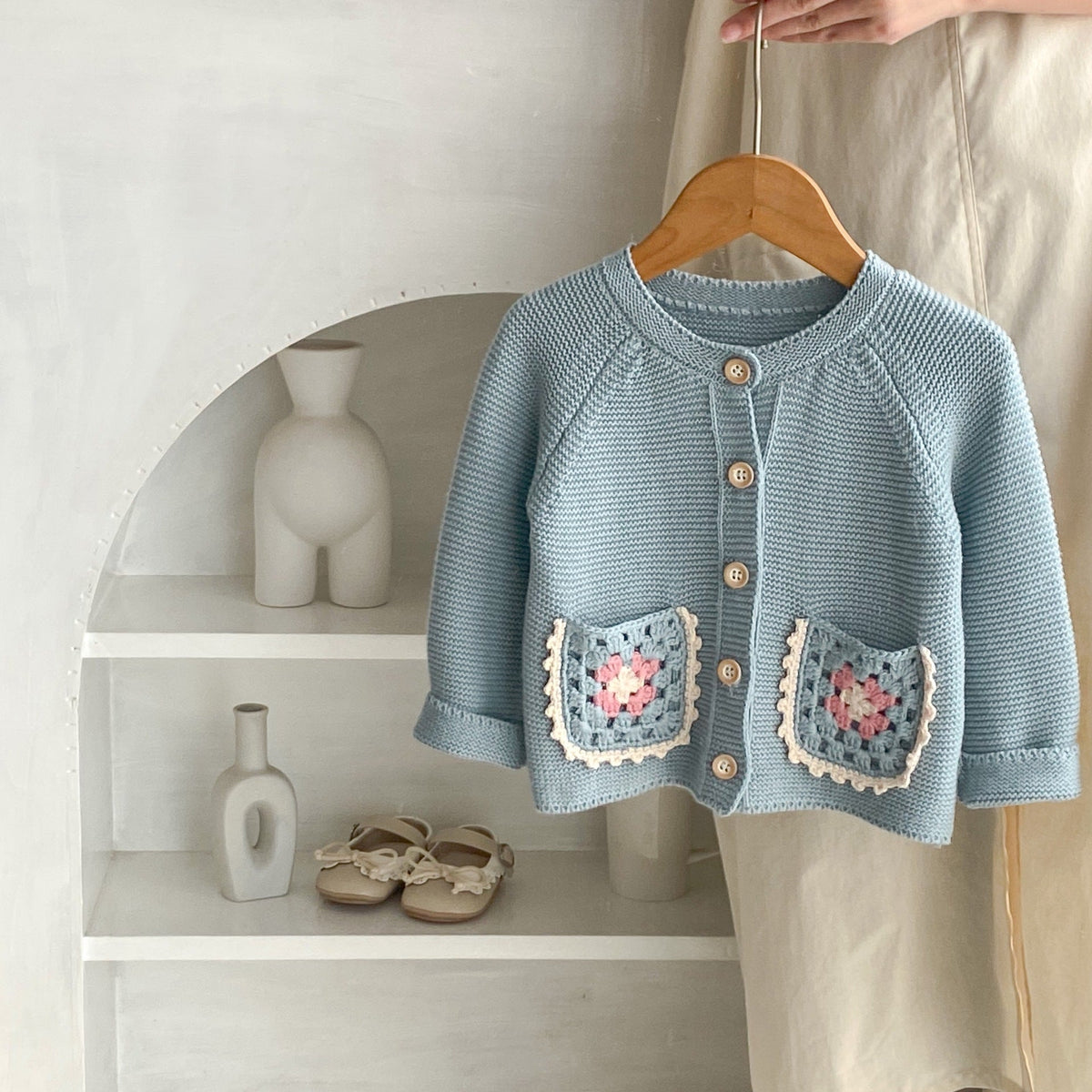 Smokey blue knit cardigan with round collar and button front, crochet flower pocket squares