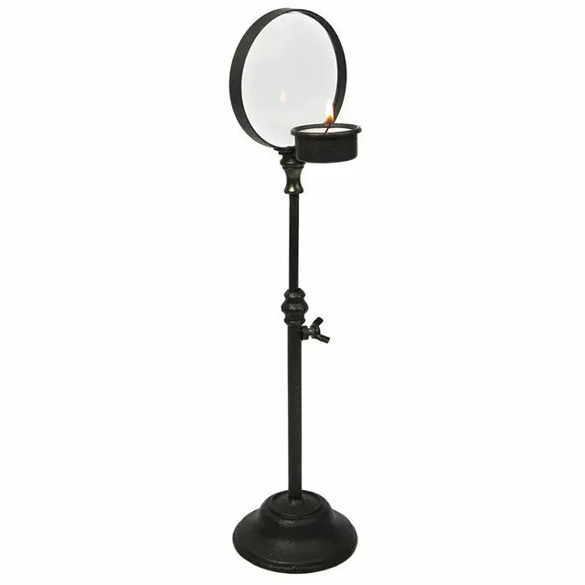 Black iron candle holder magnifier on tall stand with round glass and small flame