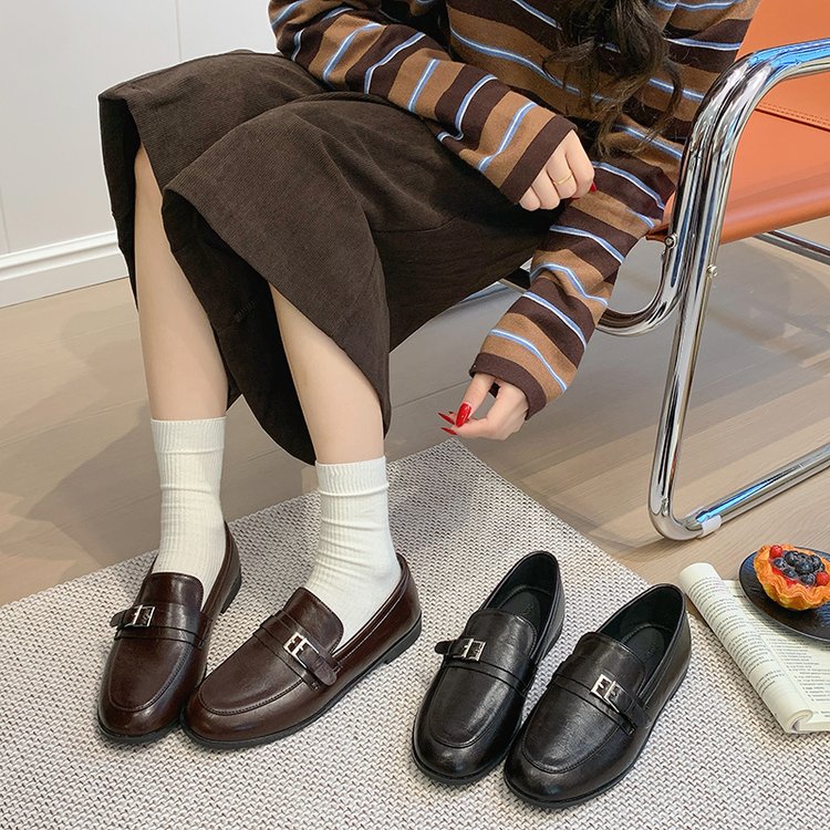 Pair of women's loafers in brown and black with buckle strap, flat low heel.