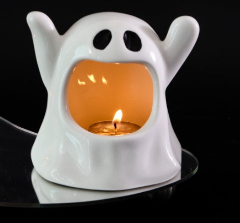 Ceramic ghost candle ornament with lit tea light, white body and glowing orange inner cavity
