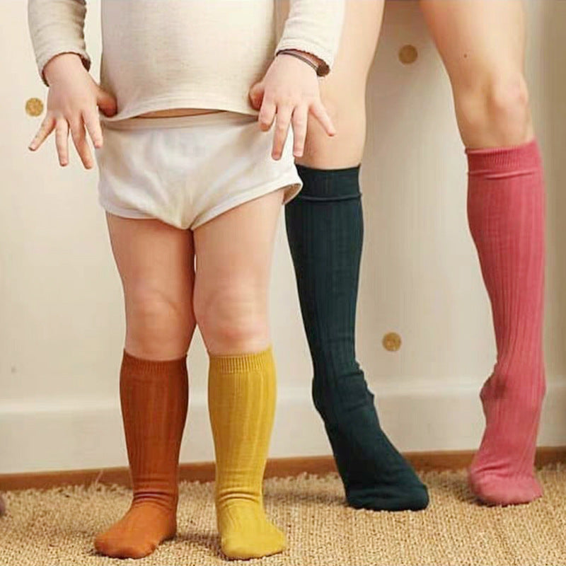 Kids mid-calf ribbed socks in brown, yellow, and pink worn on legs.