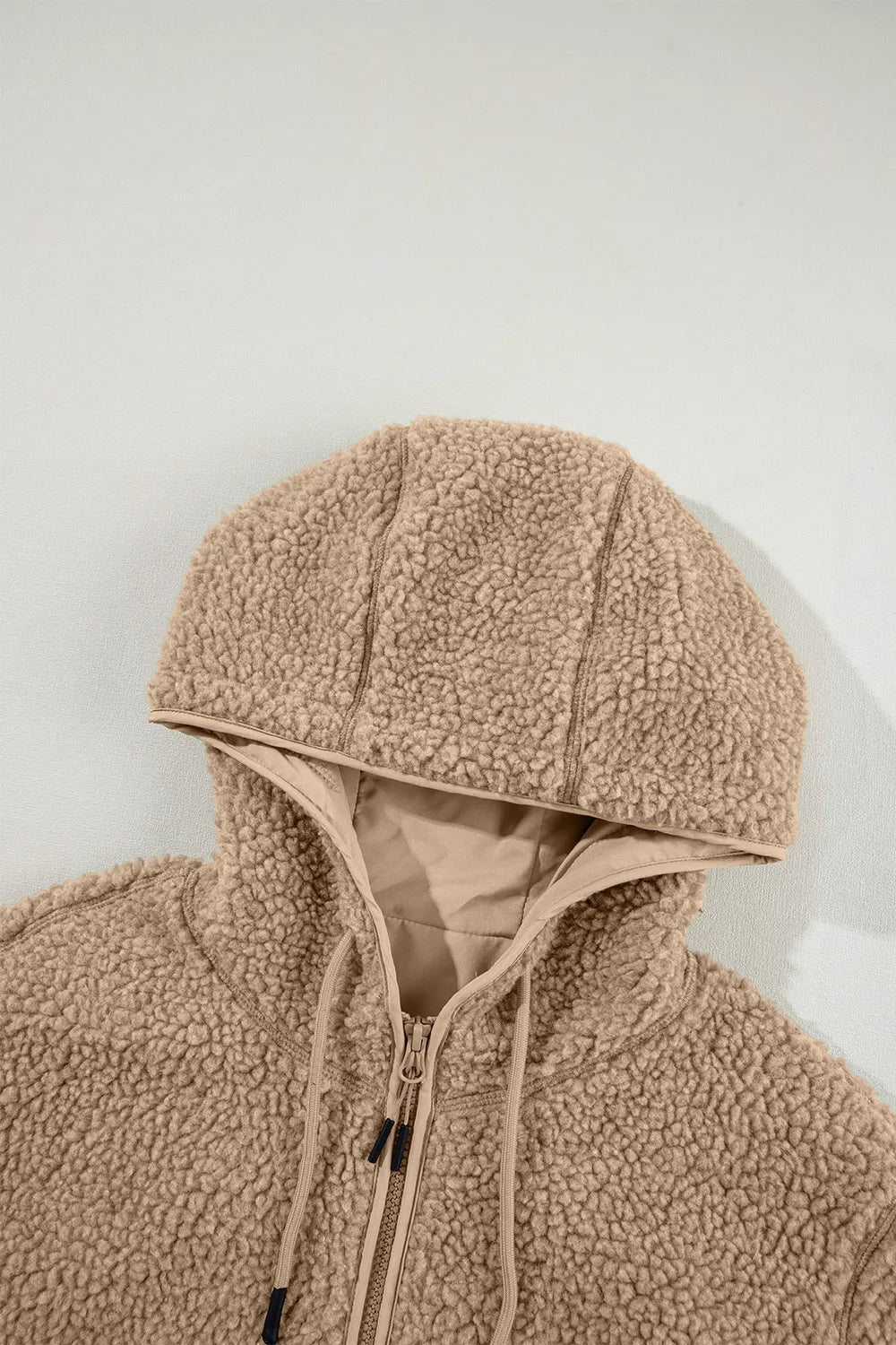 Khaki sherpa fleece hooded jacket close-up with drawstring ties and zip front