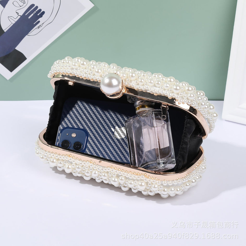 White pearl beaded lock clutch open, showing interior pocket and phone
