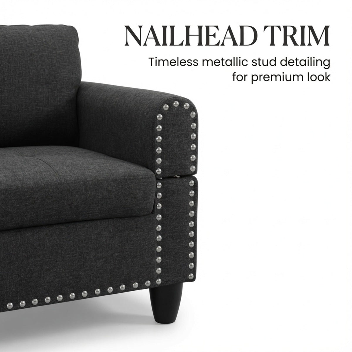 Sectional sofa arm corner with metallic stud nailhead trim on a dark gray fabric seat