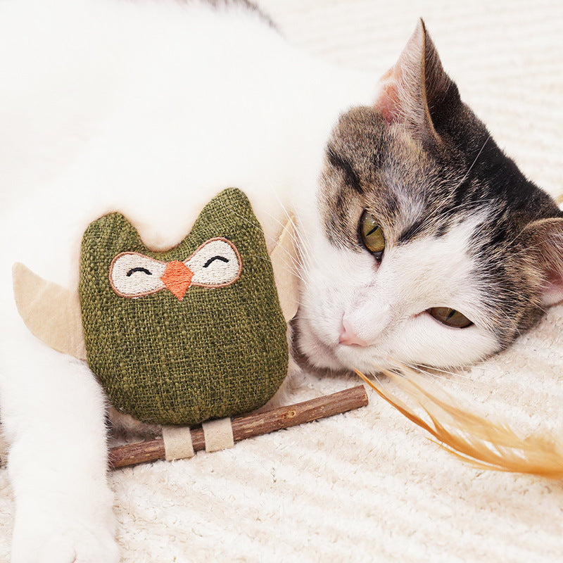 Catnip owl teething stick, green plush owl on wooden bar, cat playing
