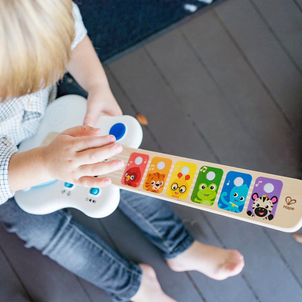 Light-up wooden guitar toy with colorful animal fretboard and blue strum light in hands