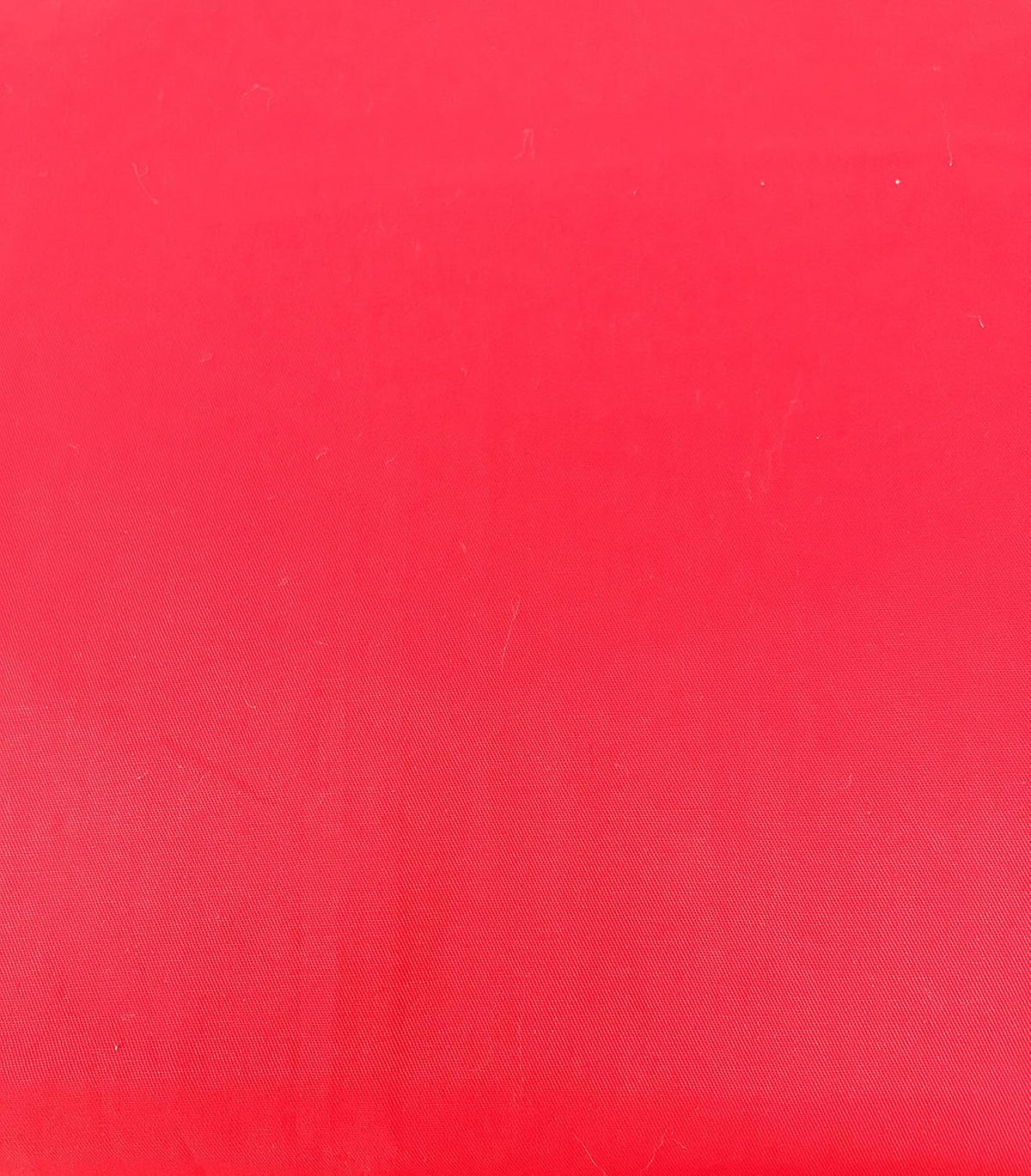 Vibrant red cotton sheet fabric close-up with fine weave texture