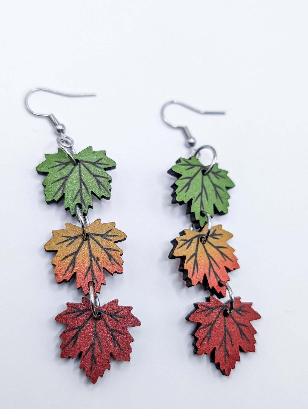 Three-layer leaf drop earrings in green, orange, and deep red with silver hooks