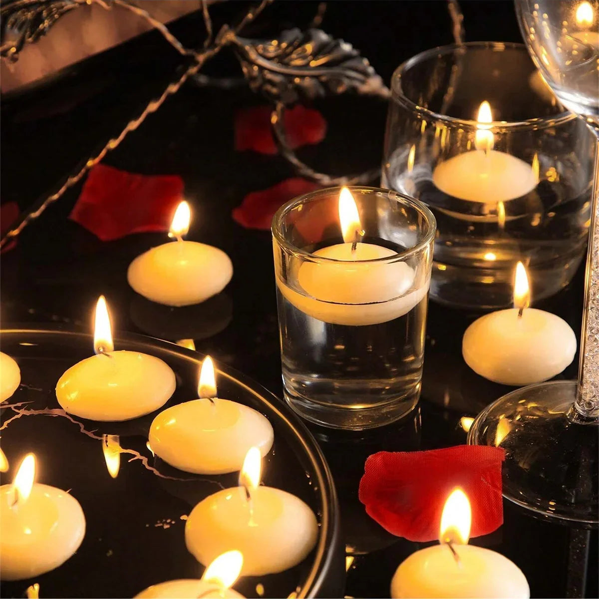 Floating tea light candles in clear cups, small flames on the surface