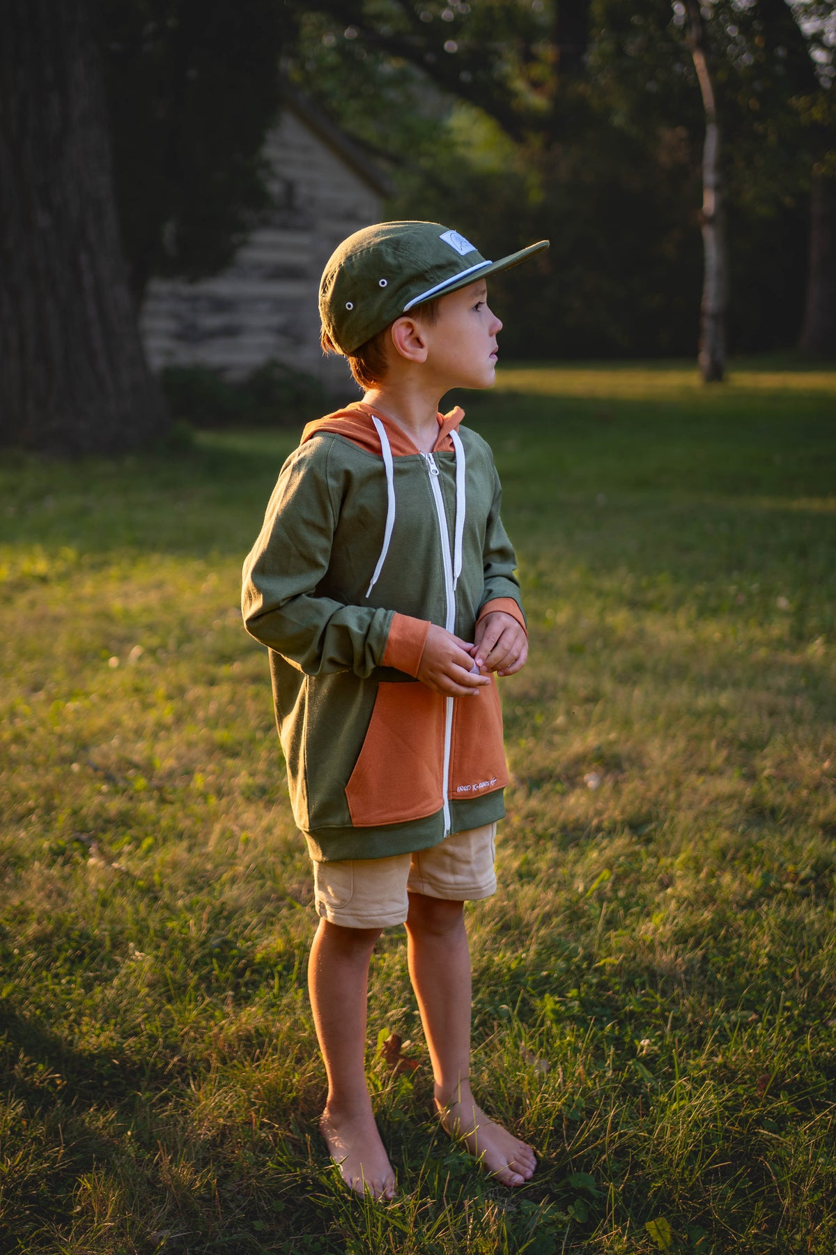 Kids green zip hoodie with orange front panel and hood, white drawcords