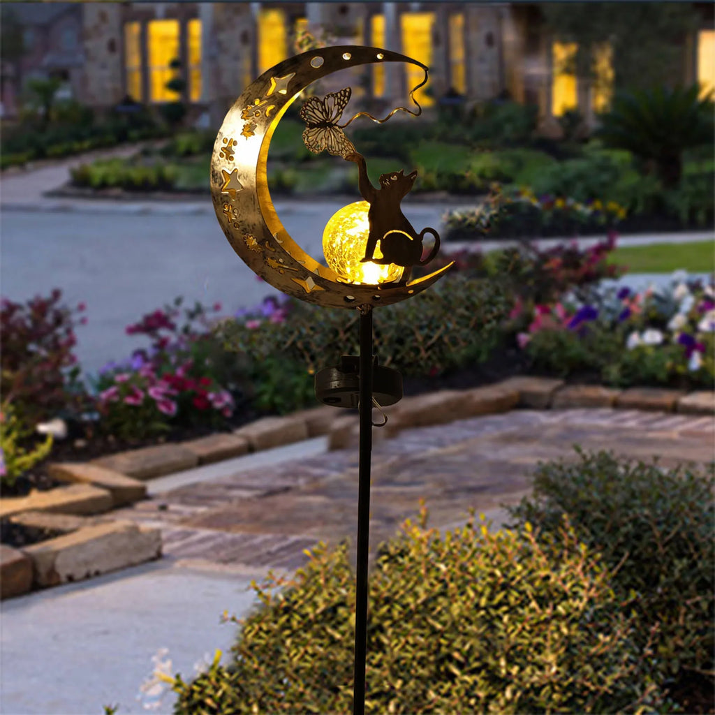 Solar moon-shaped outdoor lamp with cat silhouette and warm glowing bulb on a black stake.