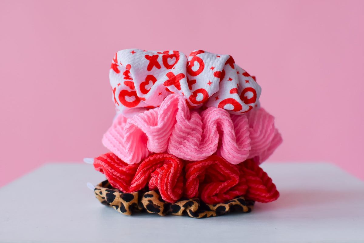 Stacked scrunchies: pink ribbed scrunchy and red patterned fabric