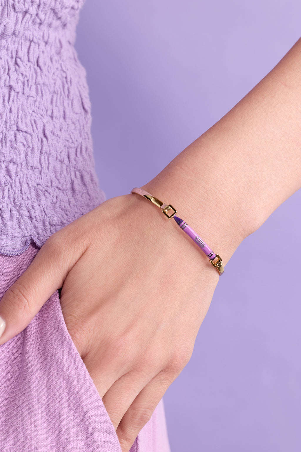 Purple crayon-style tension bangle on wrist with gold-tone clasps