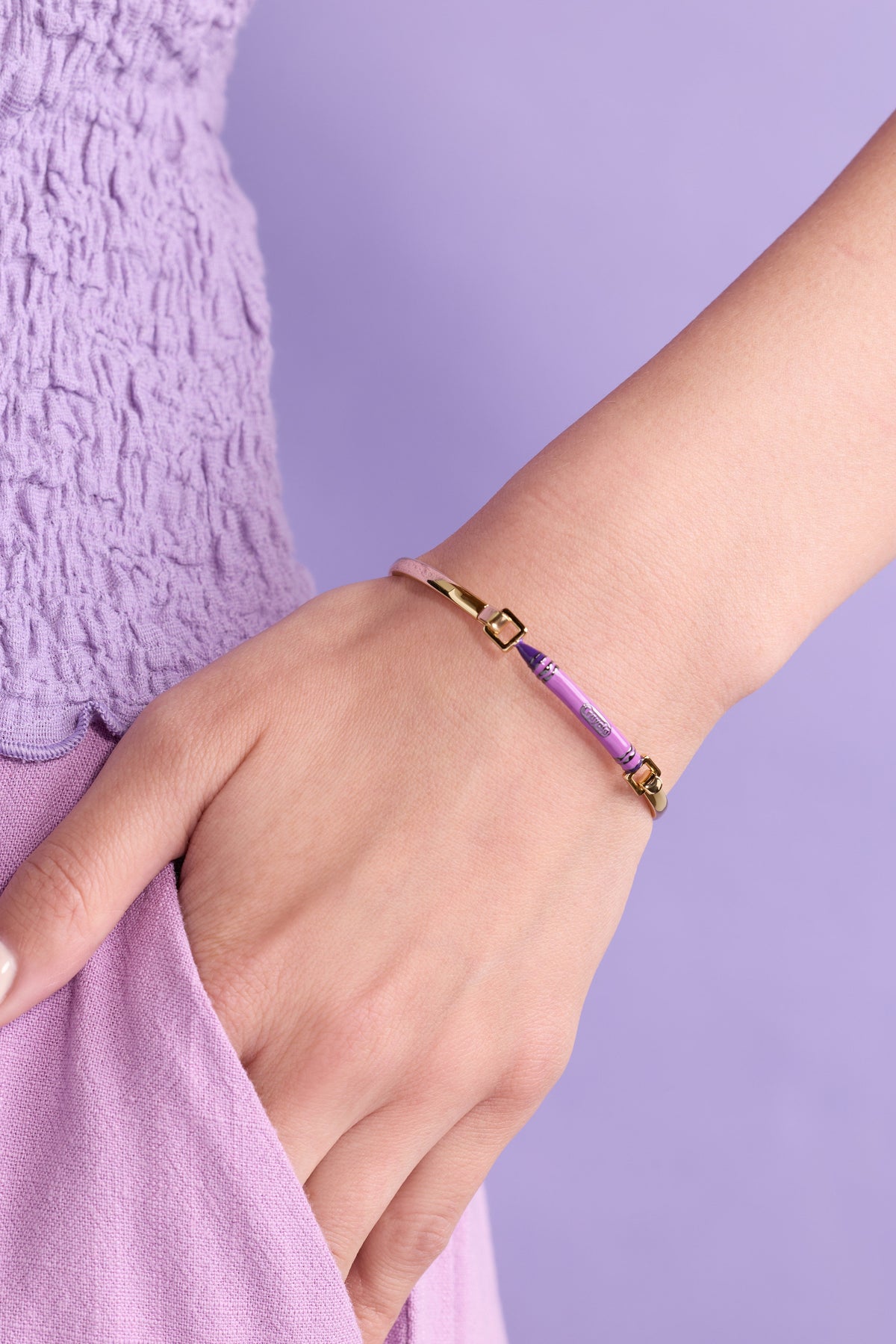 Purple crayon-style tension bangle on wrist with gold-tone clasps