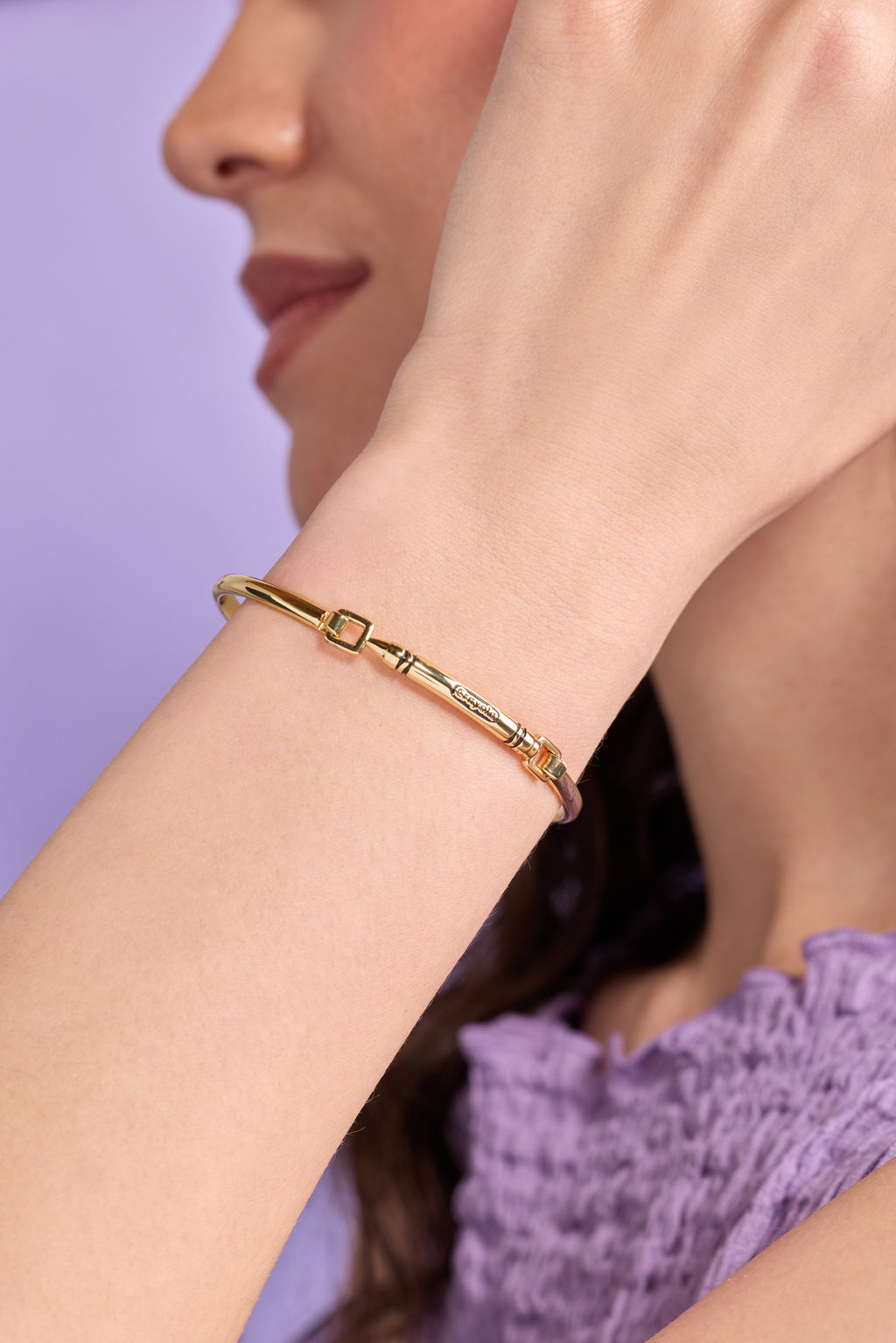 Gold Crayola crayon tension bangle on wrist with square clasp