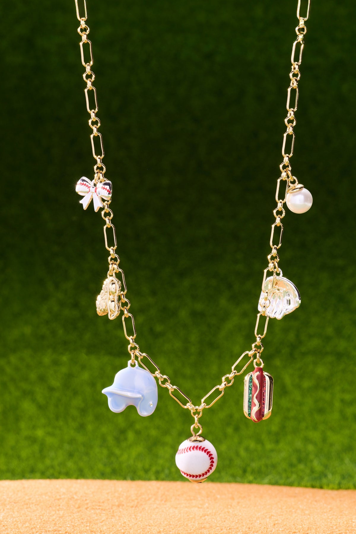 Gold-tone multi-charm necklace with pearl, hot dog, baseball, and pink bow charms