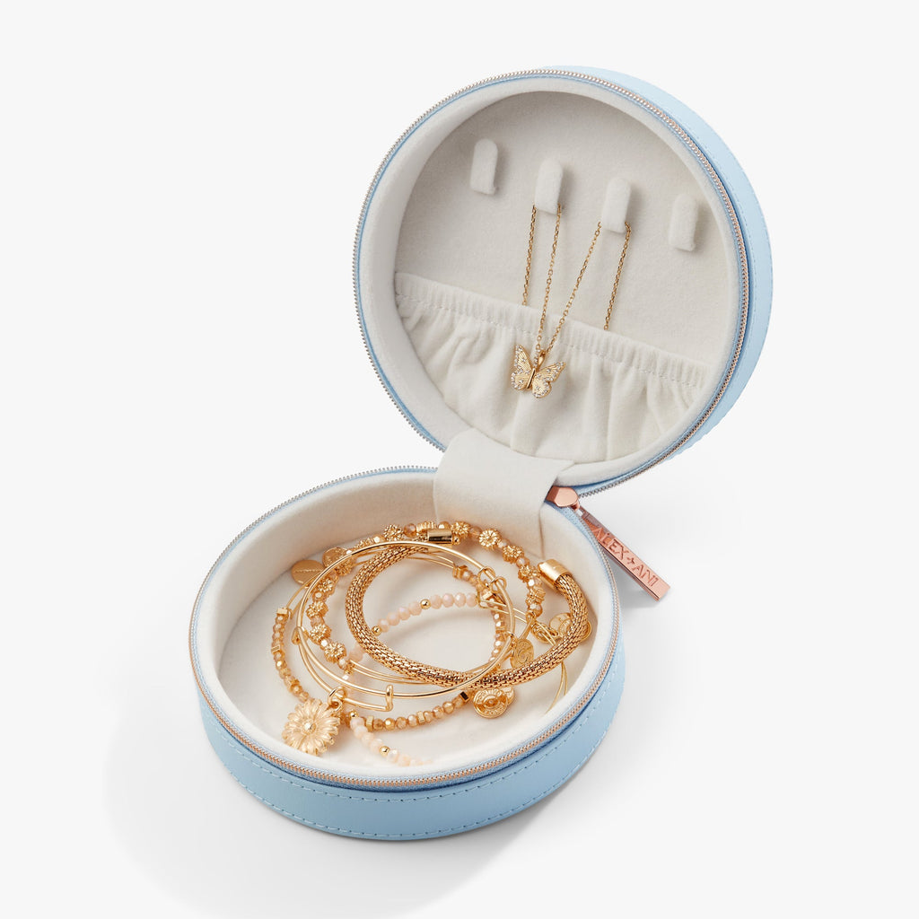 Light blue round jewelry case open with gold necklaces and bracelets on white lining