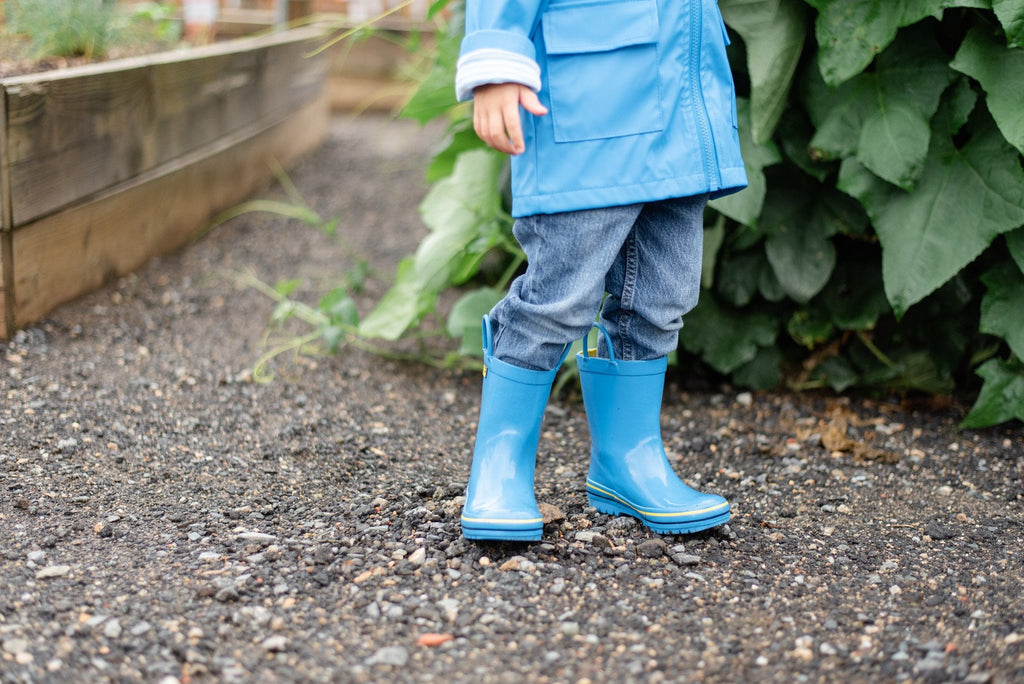 Blue rain boots on a child, yellow-trim soles visible