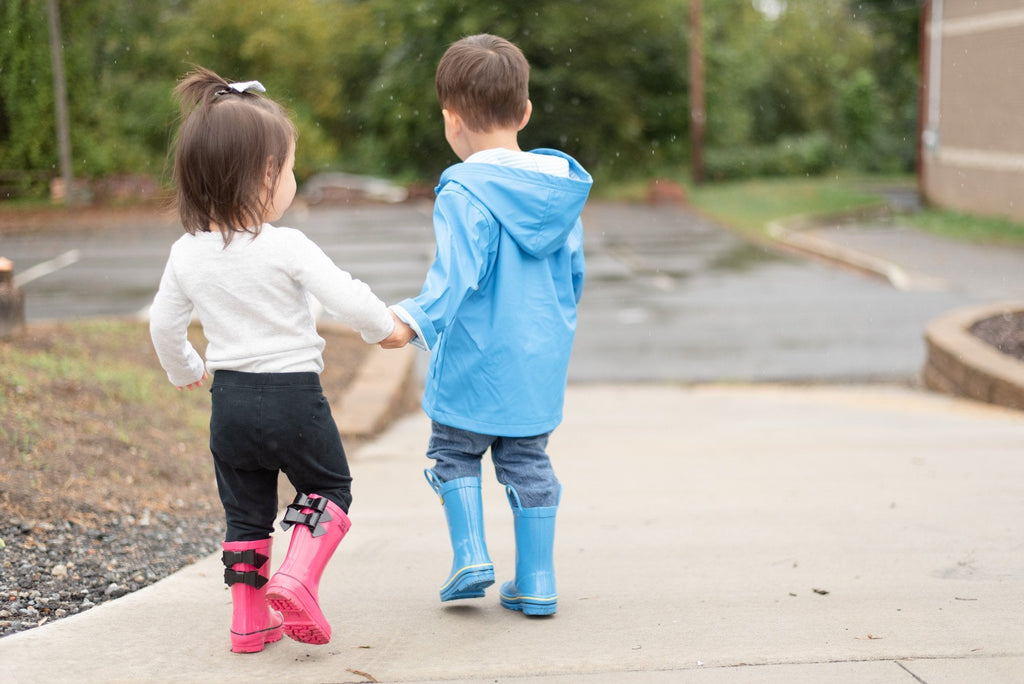 Blue rain boots with yellow trim on kids standing outside