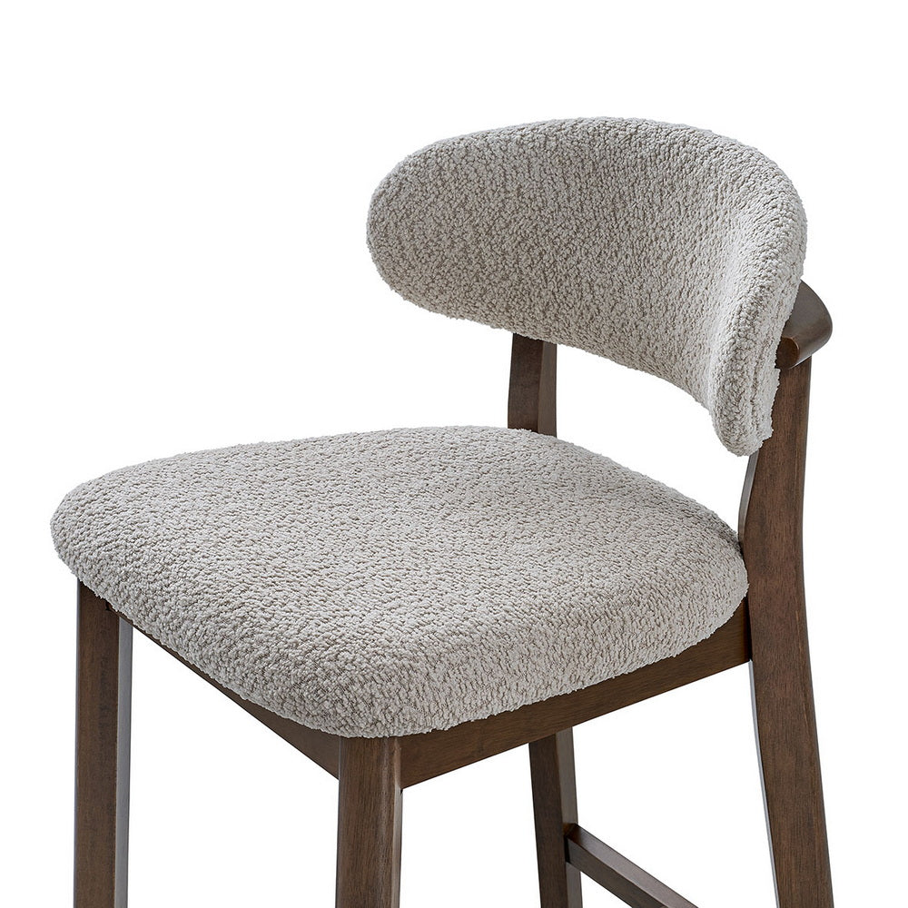 Up-close light gray upholstered bar stool seat and rounded back on dark wood frame