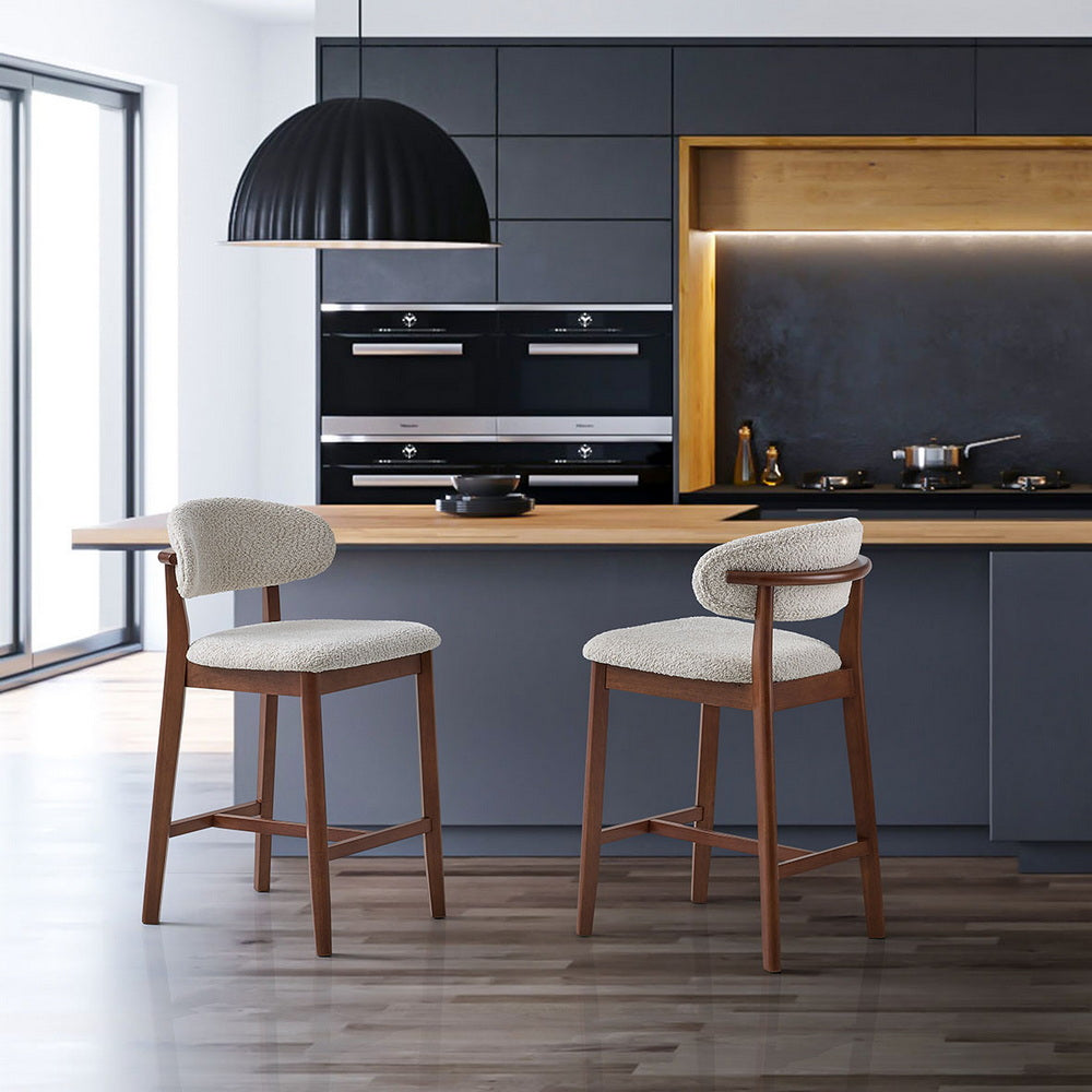 Two light gray upholstered counter bar stools with dark wood legs in modern kitchen setting