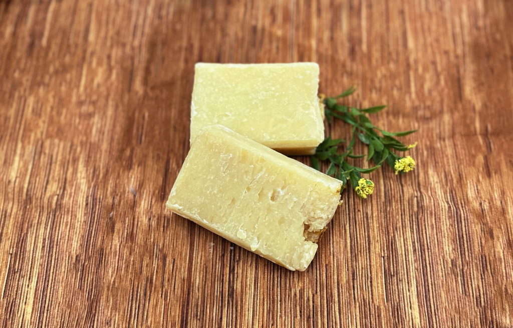Two pale yellow soap bars with small green herb sprigs