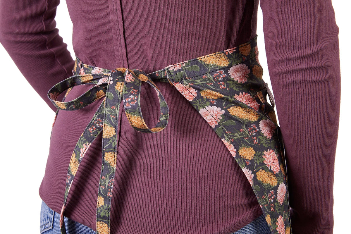Floral half apron with bow-tie waist and long waist ties, dark base with pink flowers