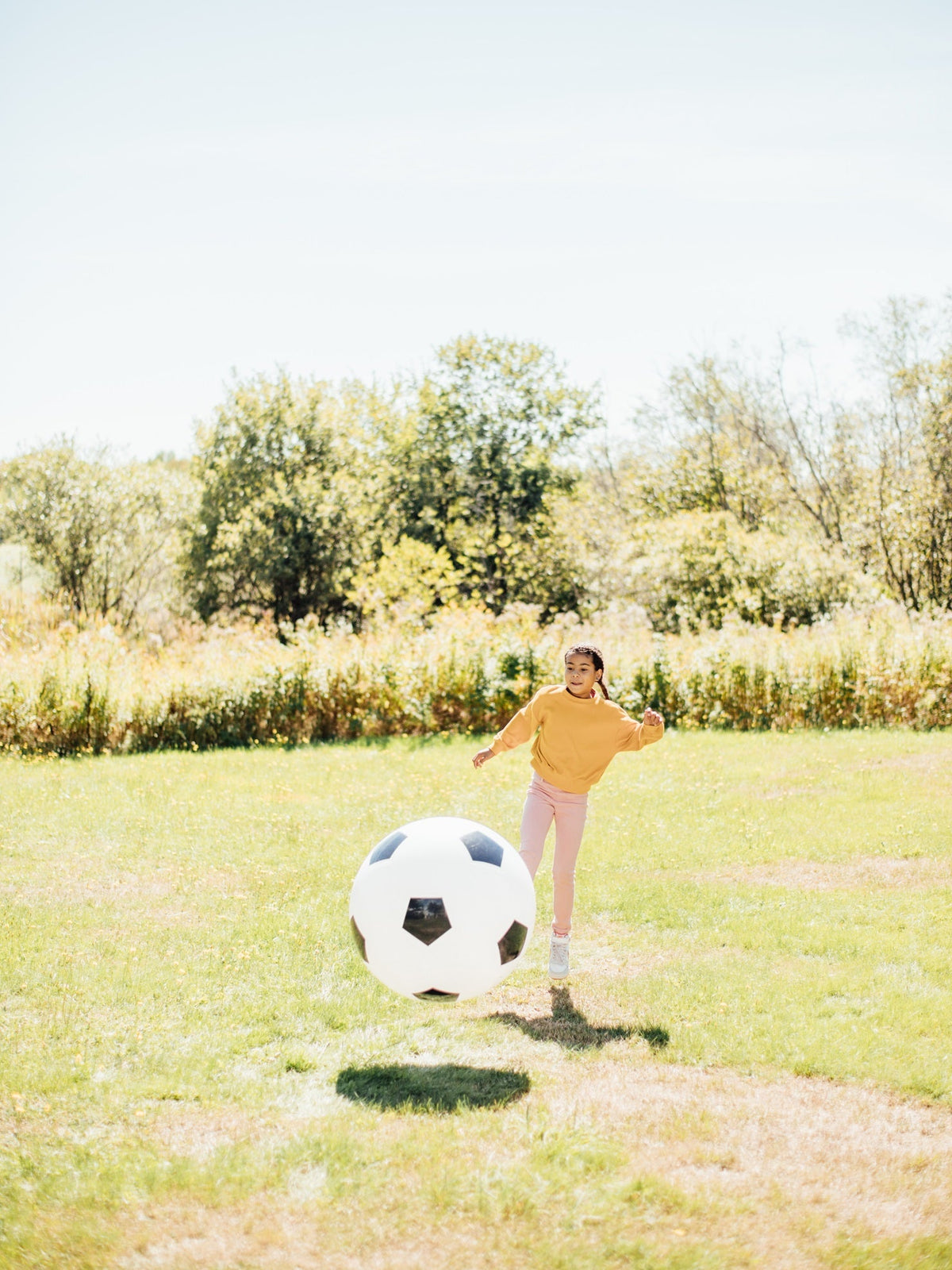 White soccer ball with black pentagon pattern near a child outdoors