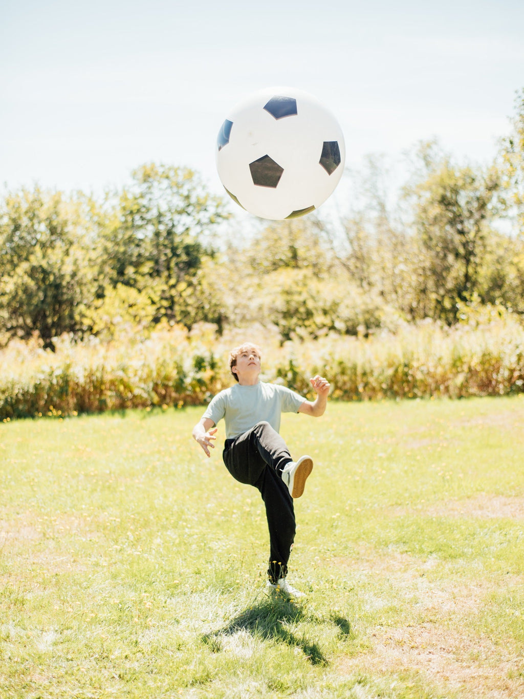 White soccer ball with black pentagon pattern mid-air during play