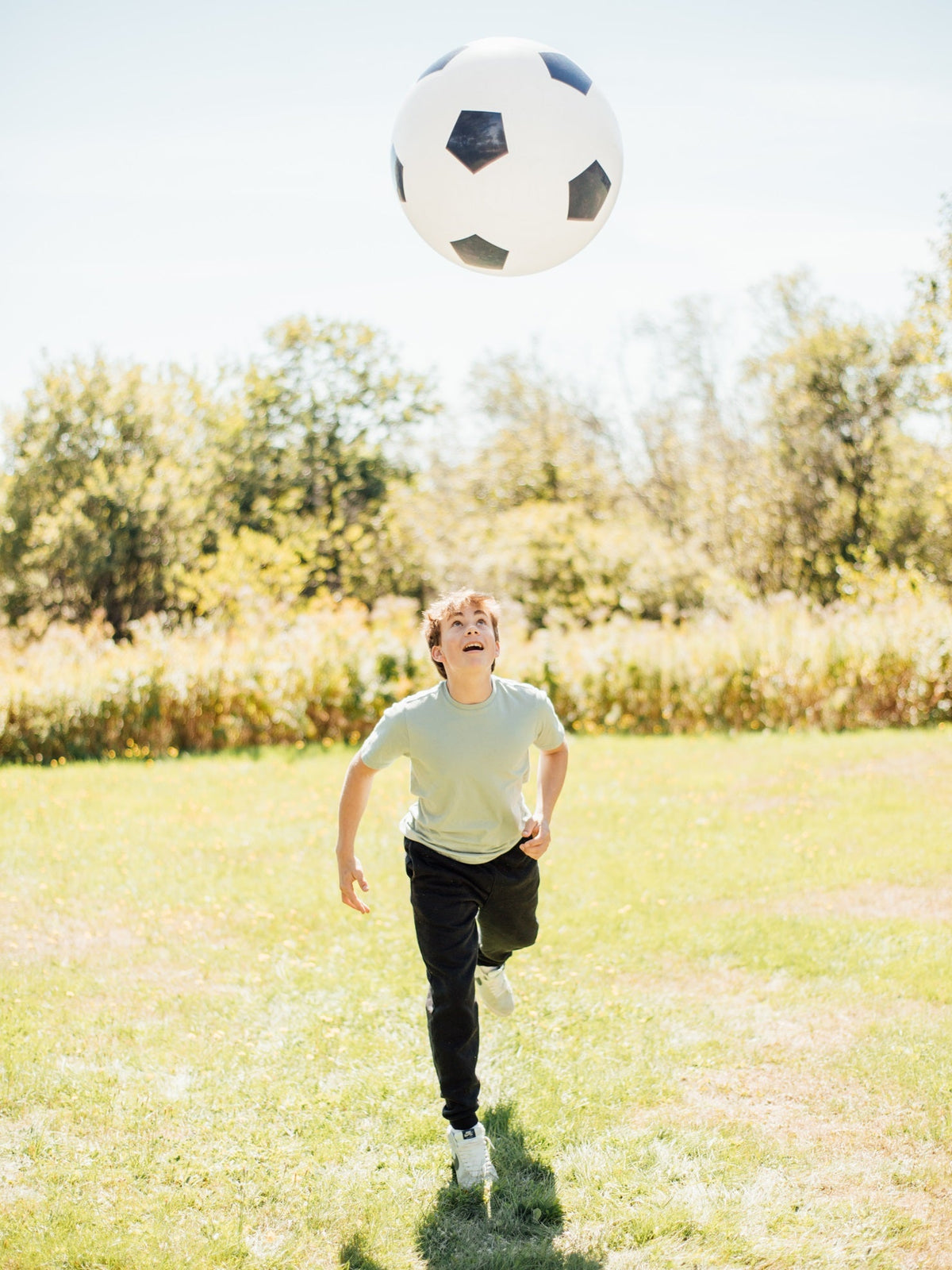 White soccer ball with black pentagon pattern floating above a runner
