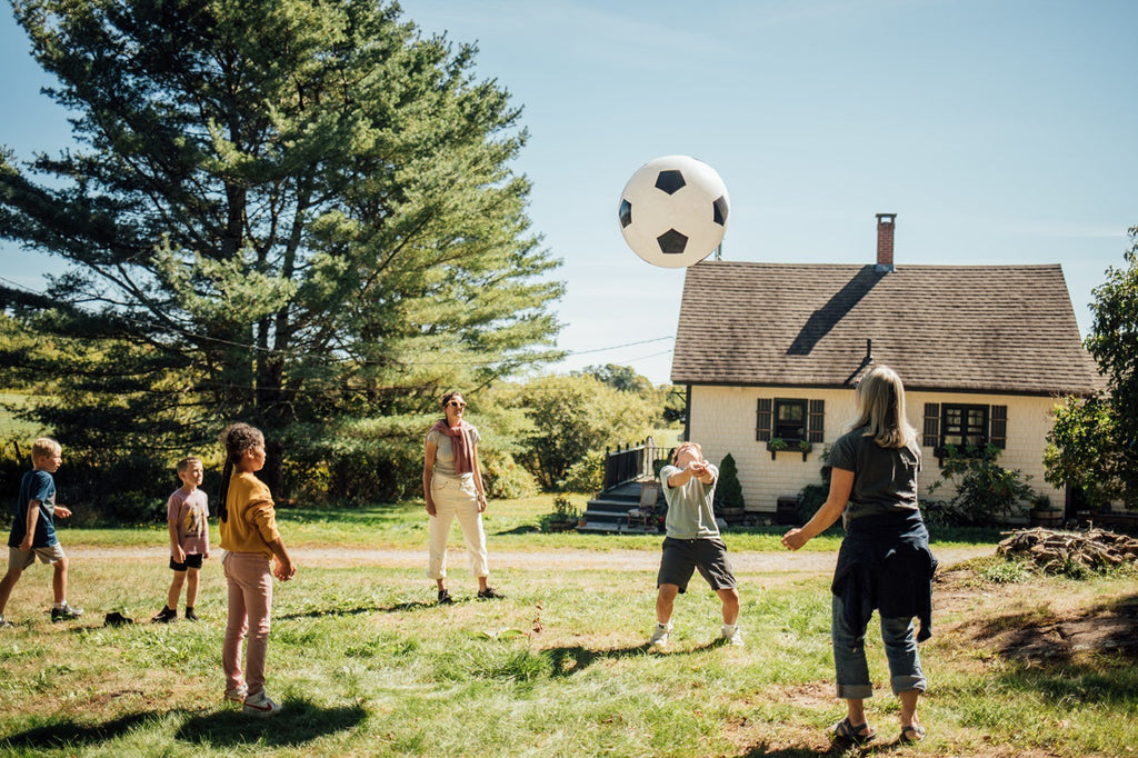 White soccer ball with black pentagon pattern above a backyard group at play