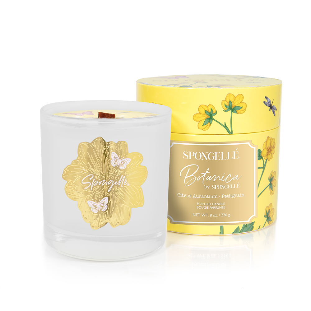 Yellow Botanica scented candle jar with gold floral label and visible wick tab
