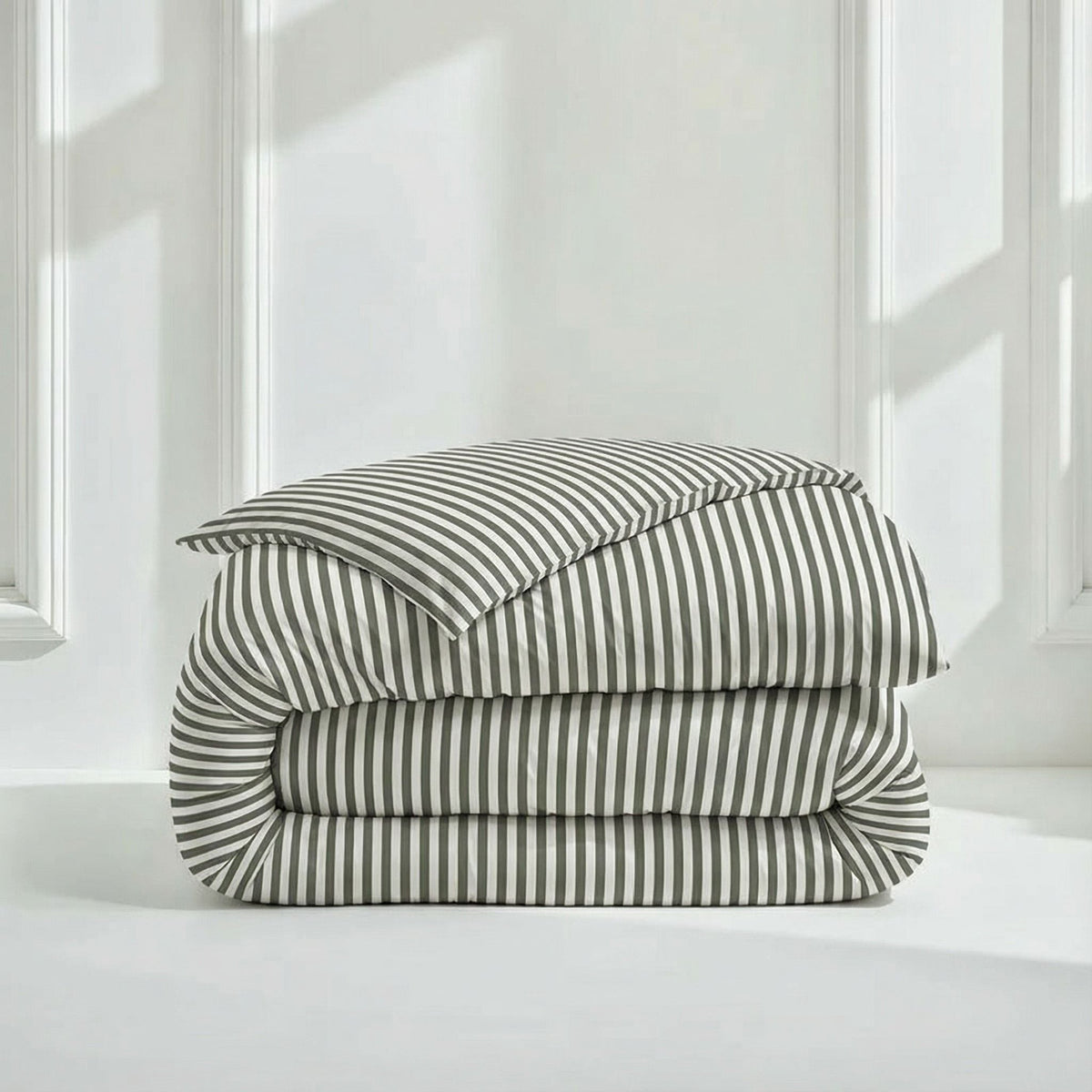 Folded striped sateen comforter with matching pillow shams, white and dark gray.
