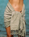 Light gray sand-free beach towel wrapped around a person, fringed edge detail.