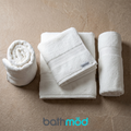 Set of four white bath towels, folded and stacked with border trim