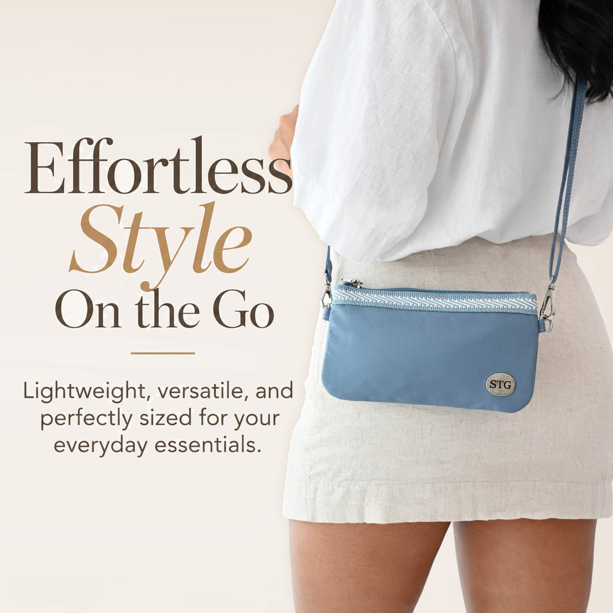 Blue crossbody phone clutch on shoulder with zip top and round STG logo badge