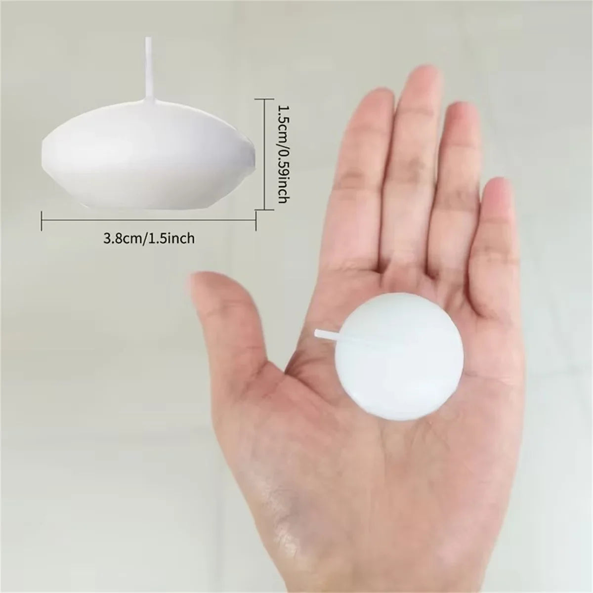 White floating candle disc with wick; shown in palm for size