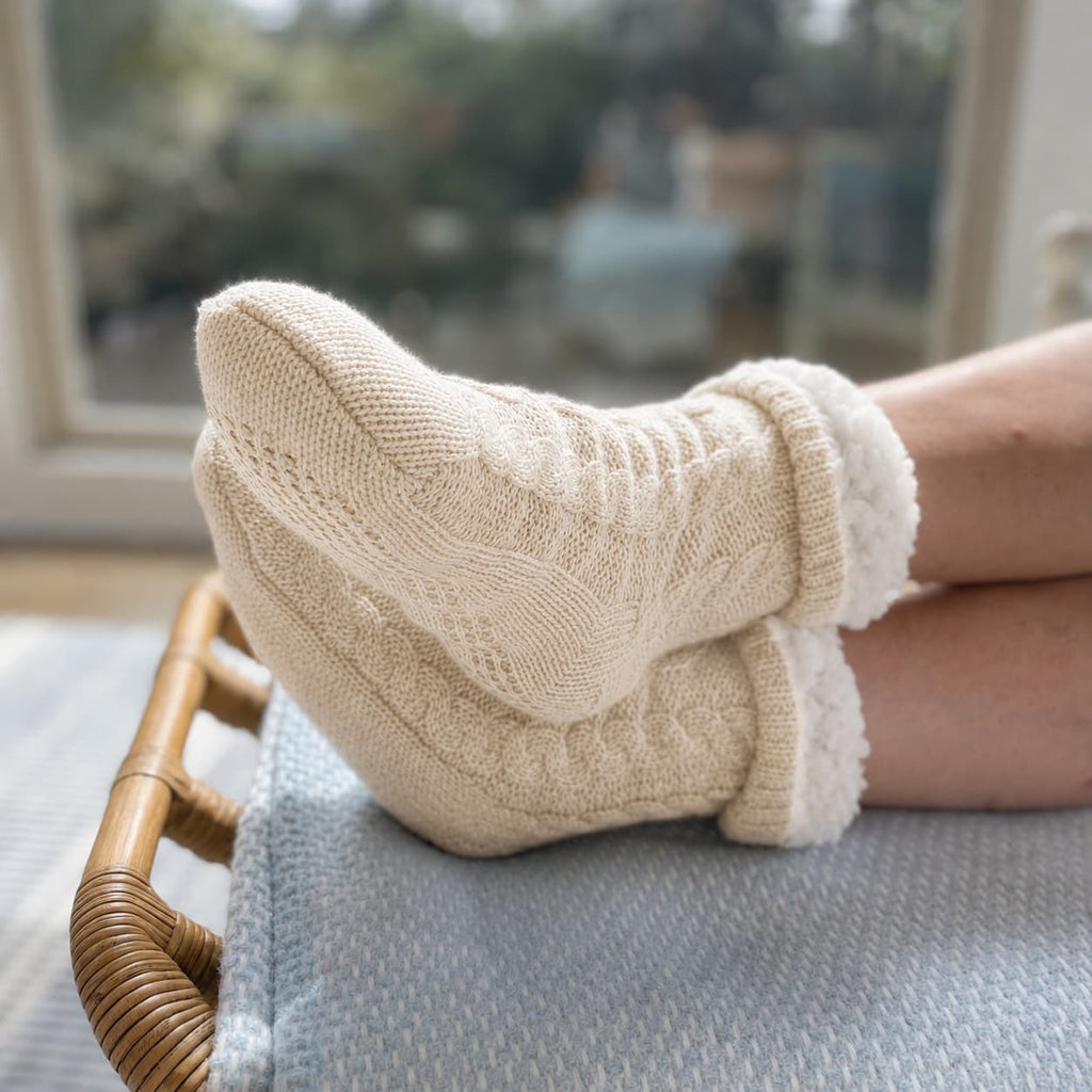 Oatmeal slipper socks with thick cable-knit texture and fuzzy cuffs