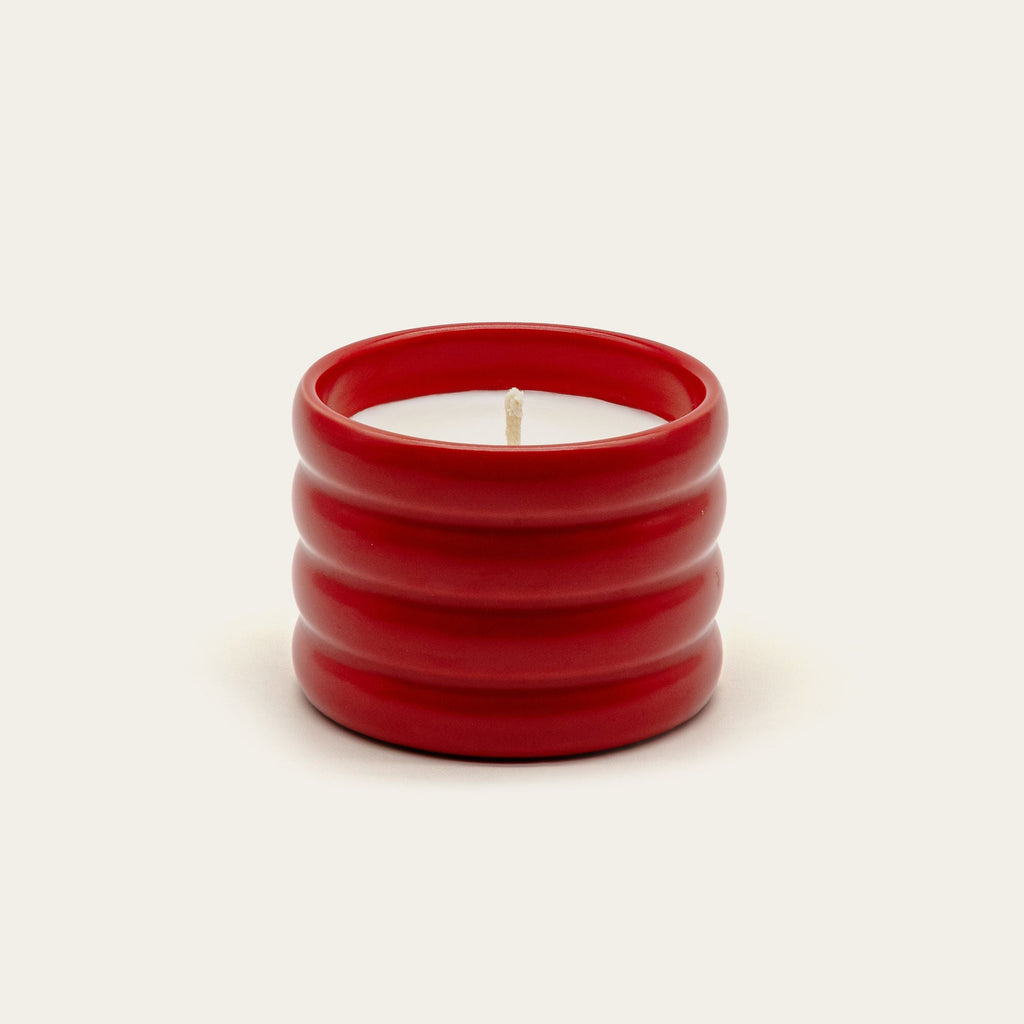 Red ribbed ceramic soy wax candle with centered lit wick