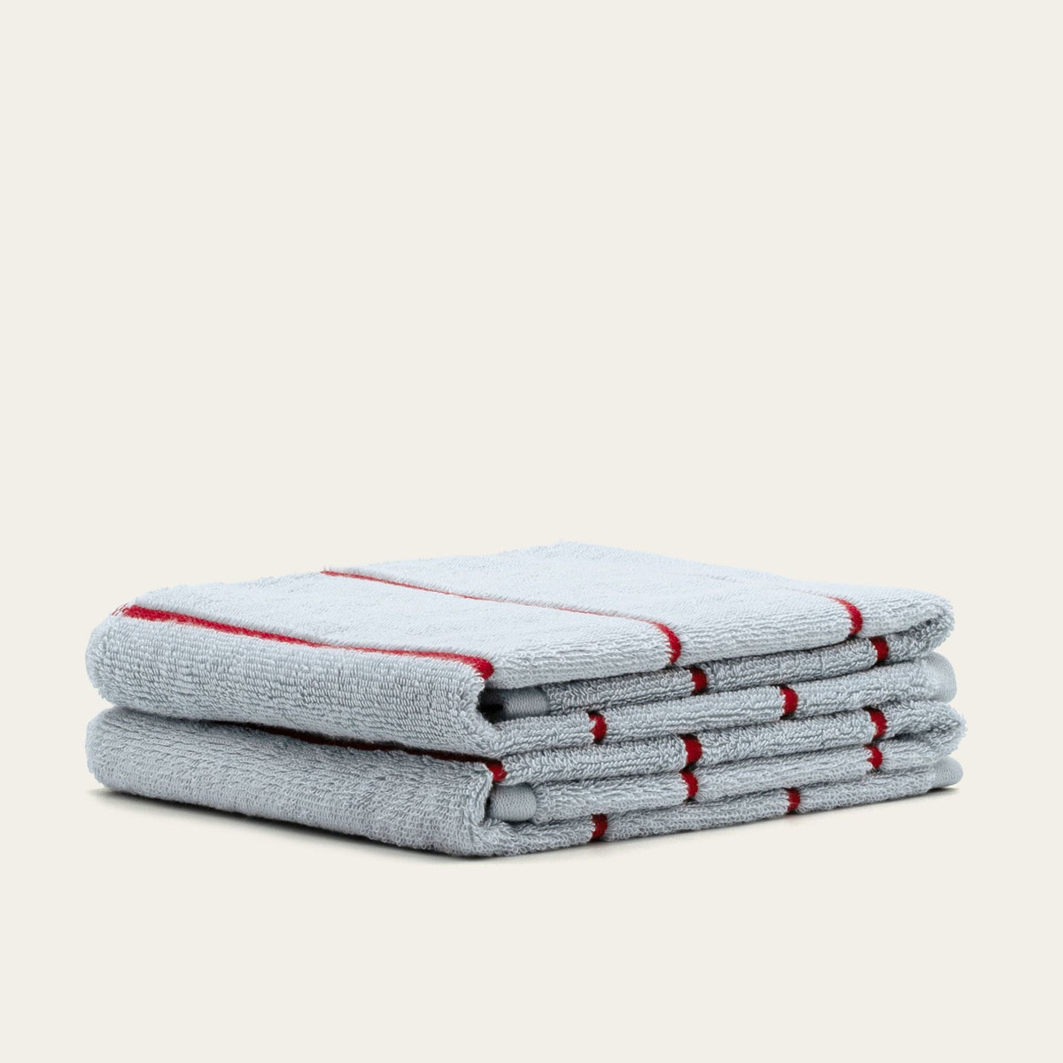 Folded gray cotton towels with red stripe accents, neatly stacked