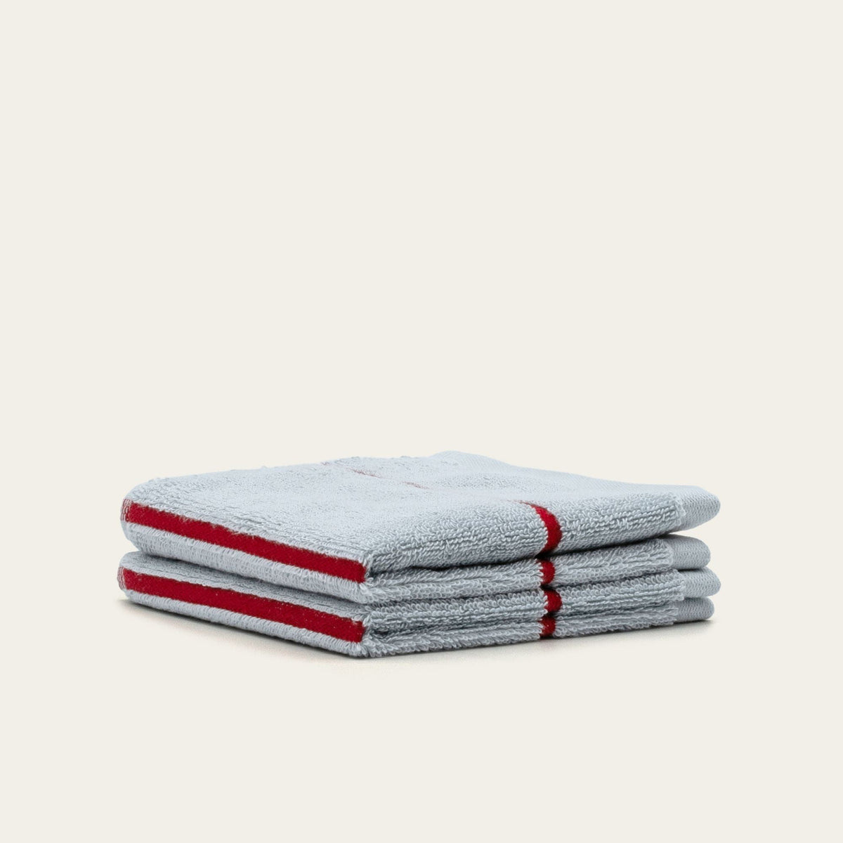 Stacked gray cotton towels with red stripe accents, folded neatly