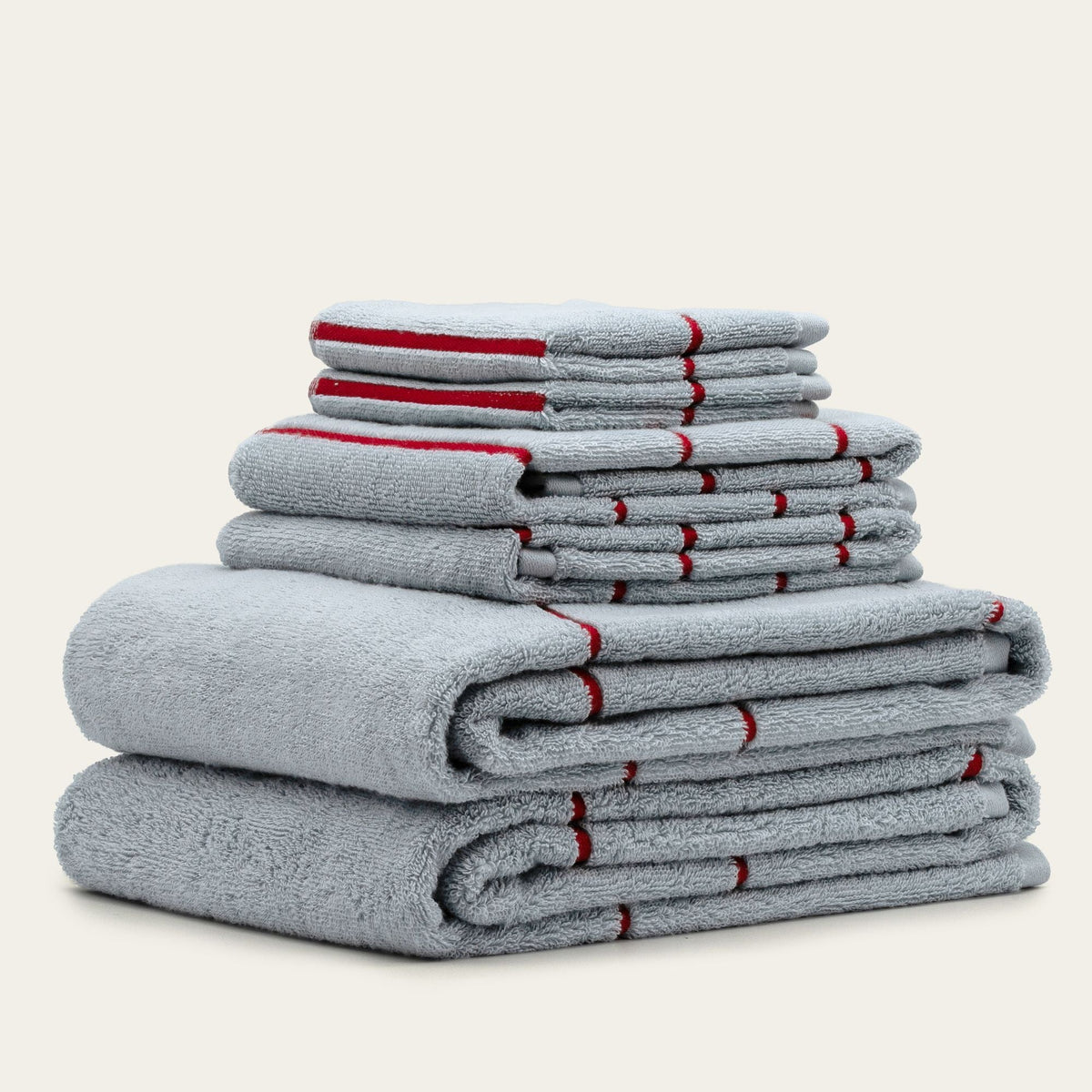 Multiple folded gray cotton towels with red stripe bands, stacked for display