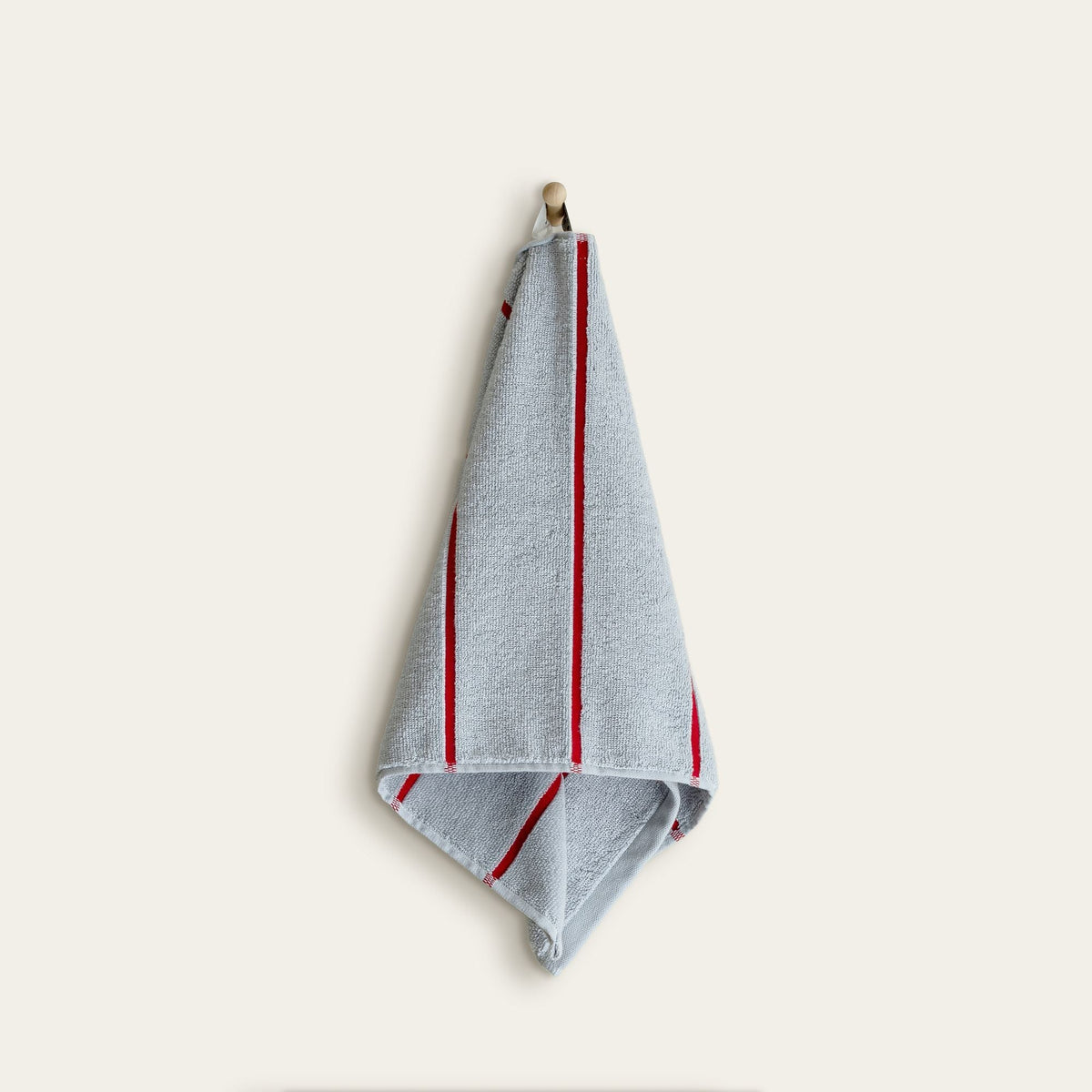 Light sky blue cotton towel with vertical red stripe accents, folded and hanging