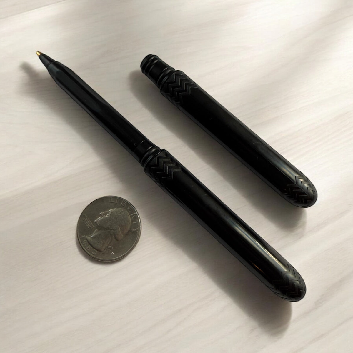 Pocket pens, two black slim pens with pointed tips and textured chevron barrels