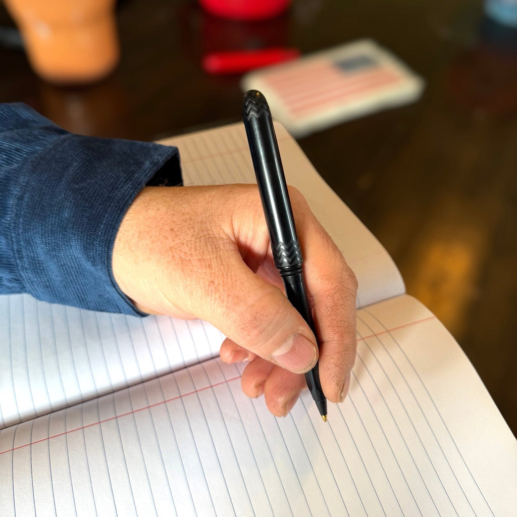 Black pocket pen held in hand, slim barrel with textured chevron grip