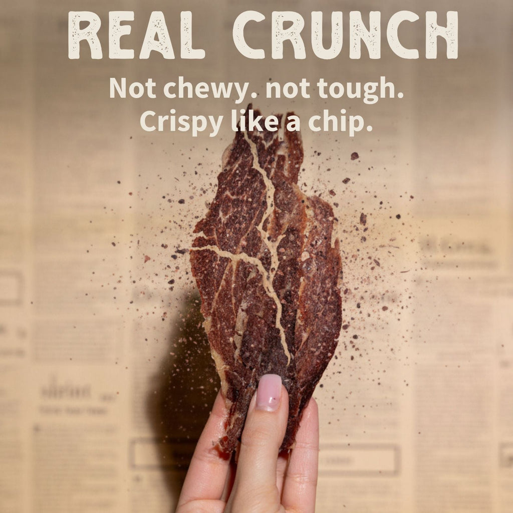 Hand holding a crunchy 2nd cut brisket meat chip