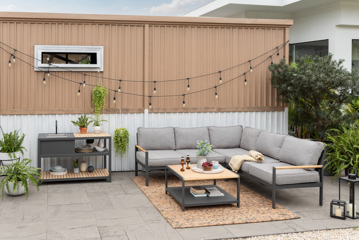 Outdoor kitchen island with stainless sink, wood countertop, gray base and open shelving